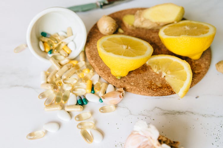 Capsules And Tablets And Sliced Lemon On A Corkboard