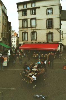 Quaint European street scene with people dining al fresco outside a charming cafe.