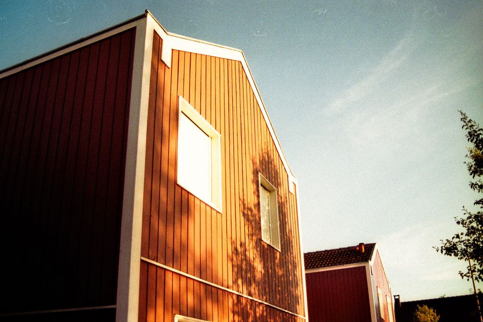 A low-angle shot of vibrant red wooden houses under a clear blue sky, capturing a modern village setting. Best Exterior Wood Paint for Irish Homes