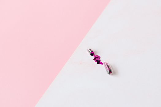 Two opened capsules with pink glitter on a pastel background offering a vibrant contrast.