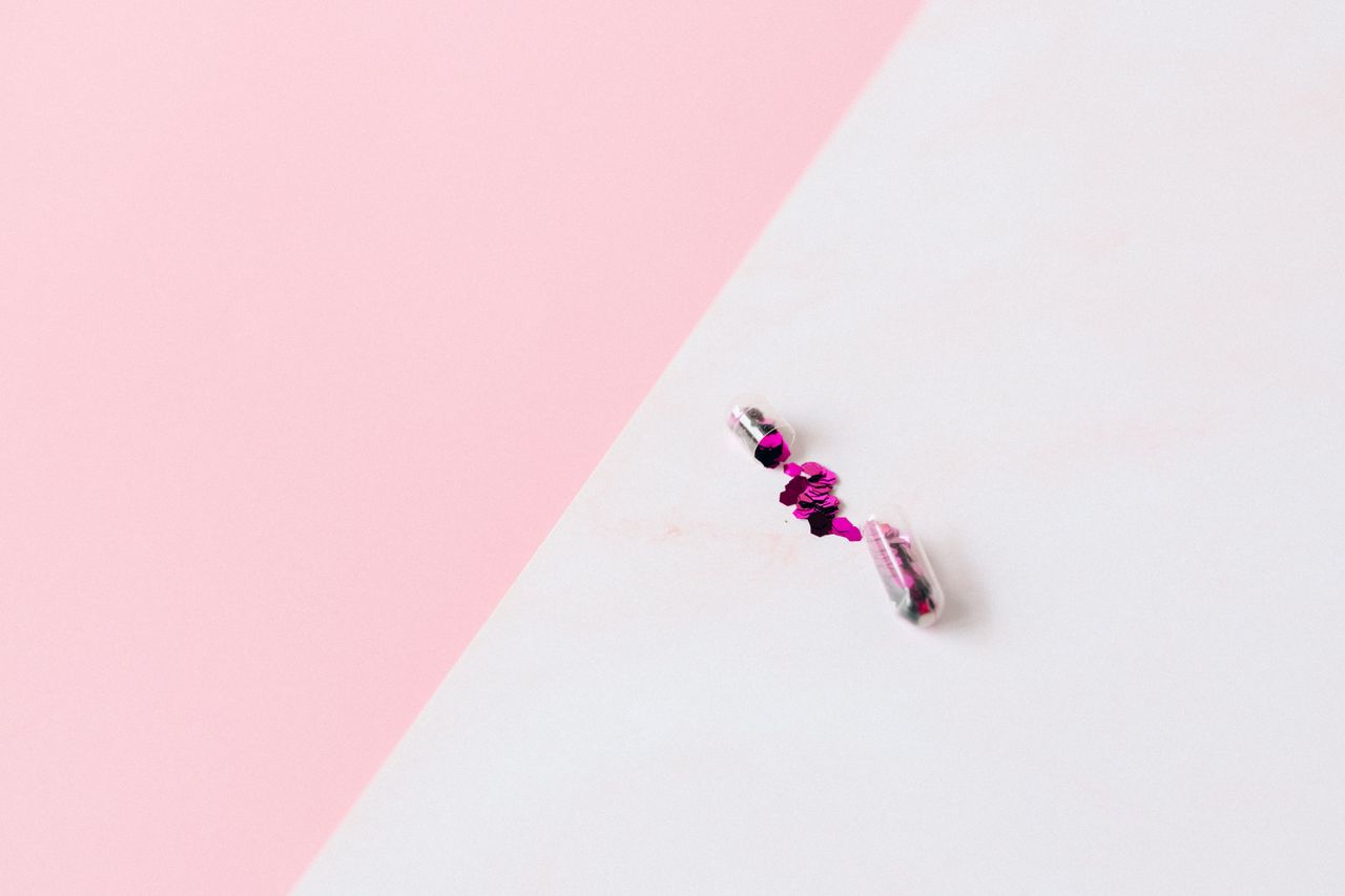 two opened capsules with pink glitter on a pastel background offering