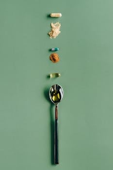 Assorted supplements and a spoon laid out on a green surface, showcasing health concepts.