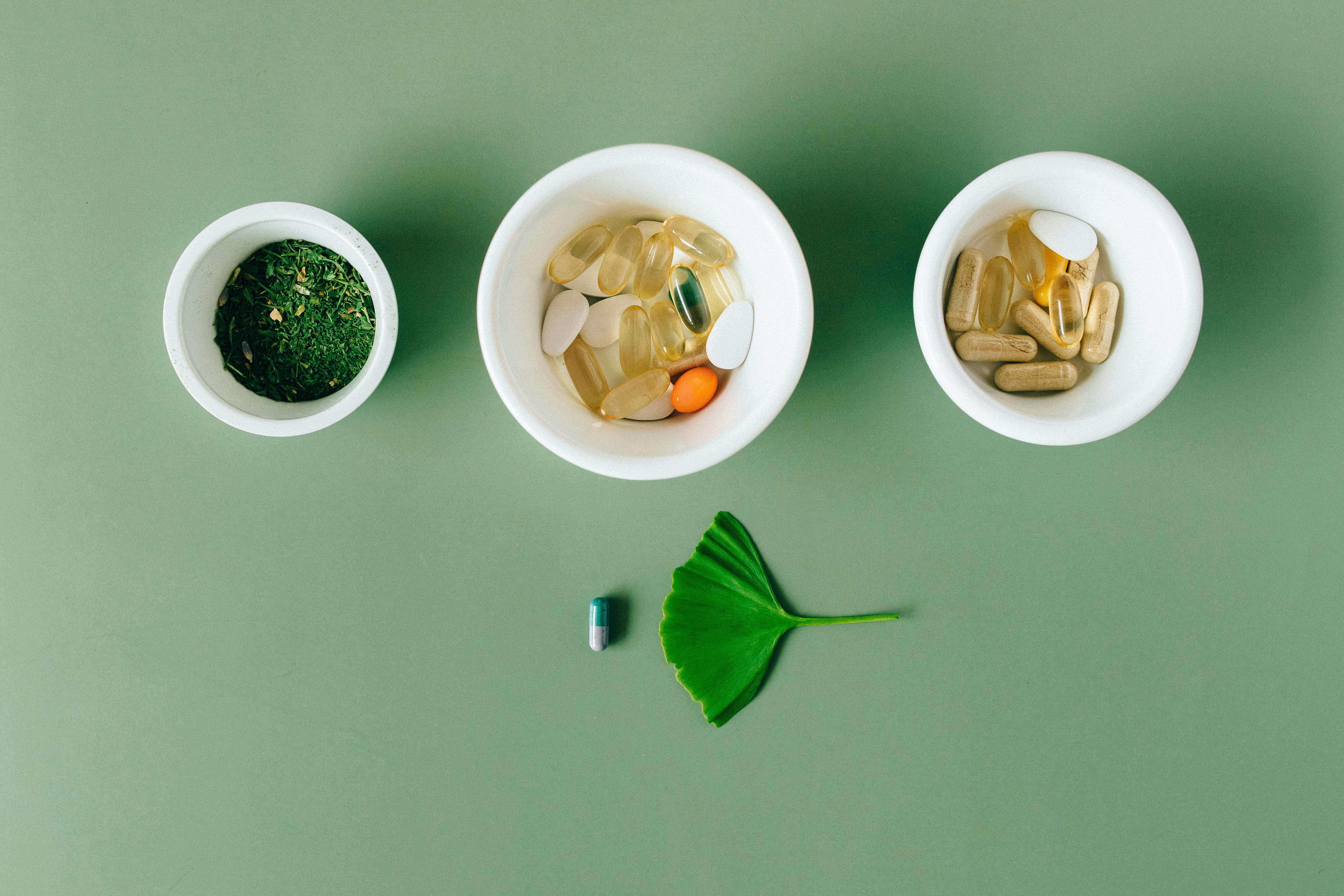 ceramic bowls with capsules and tablets on a green surface