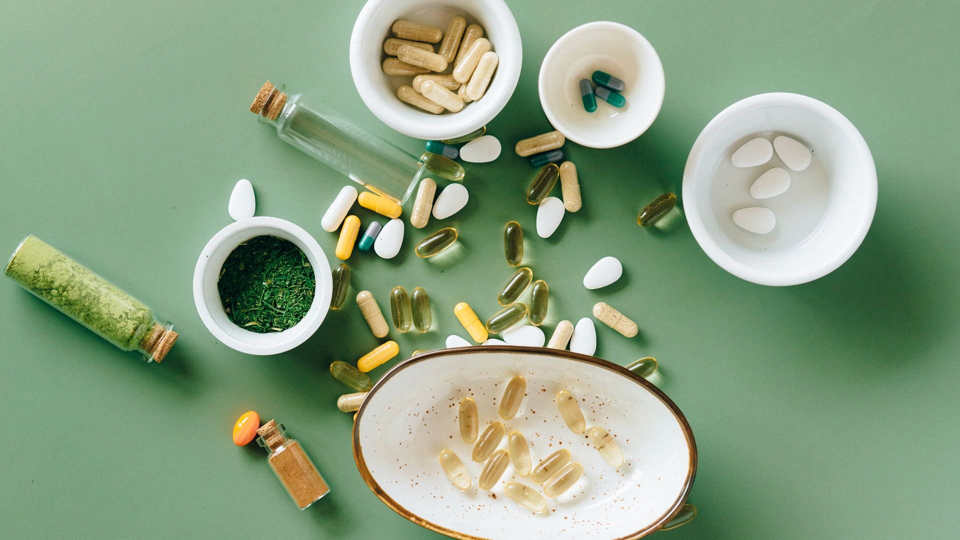 Brain Optimization Supplements: Boosting Cognitive Performance Top view of various herbal and pharmaceutical supplements in ceramic bowls on a green background — brain optimization supplements