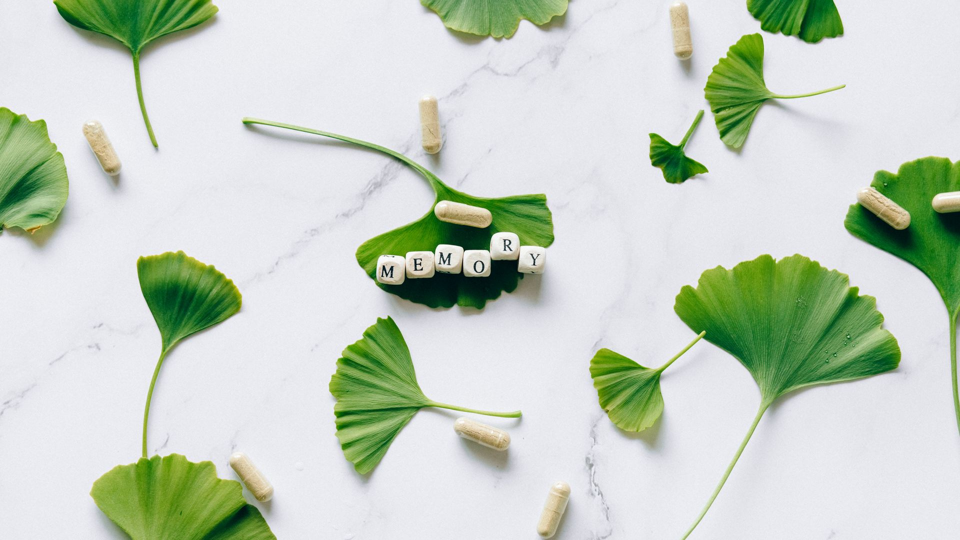 Modafinil for Memory Enhancement: Boost Your Brain Power Flat lay of ginkgo leaves with memory capsules on marble surface.