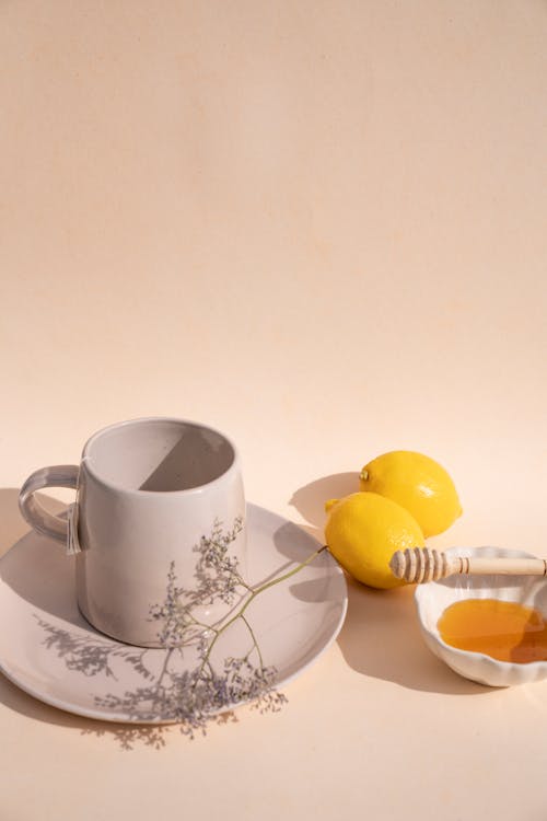 Fresh Lemons Between a Ceramic Cup and a Bowl of Honey