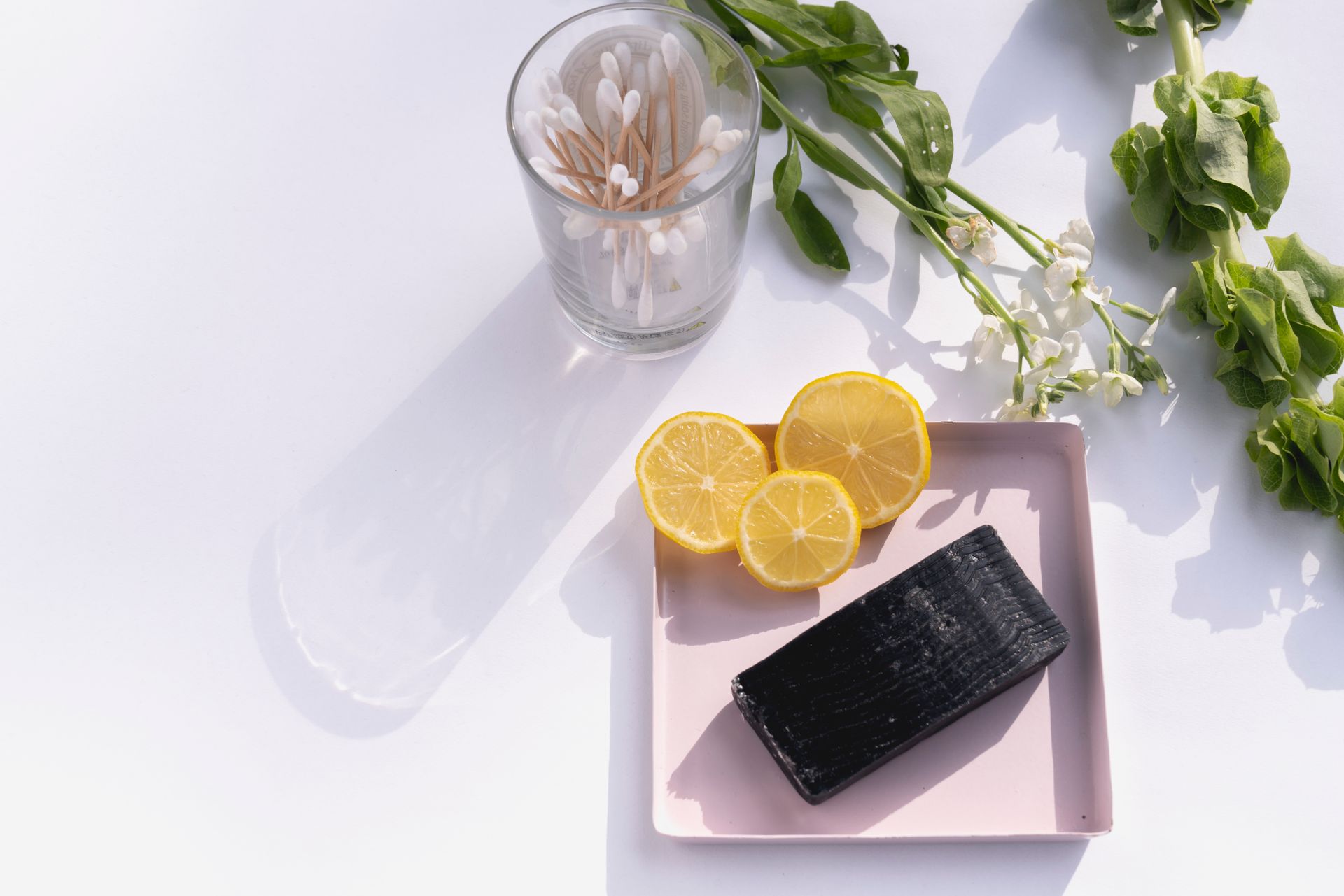 Flat lay of natural soap with lemon slices and greenery, emphasizing fresh skincare.