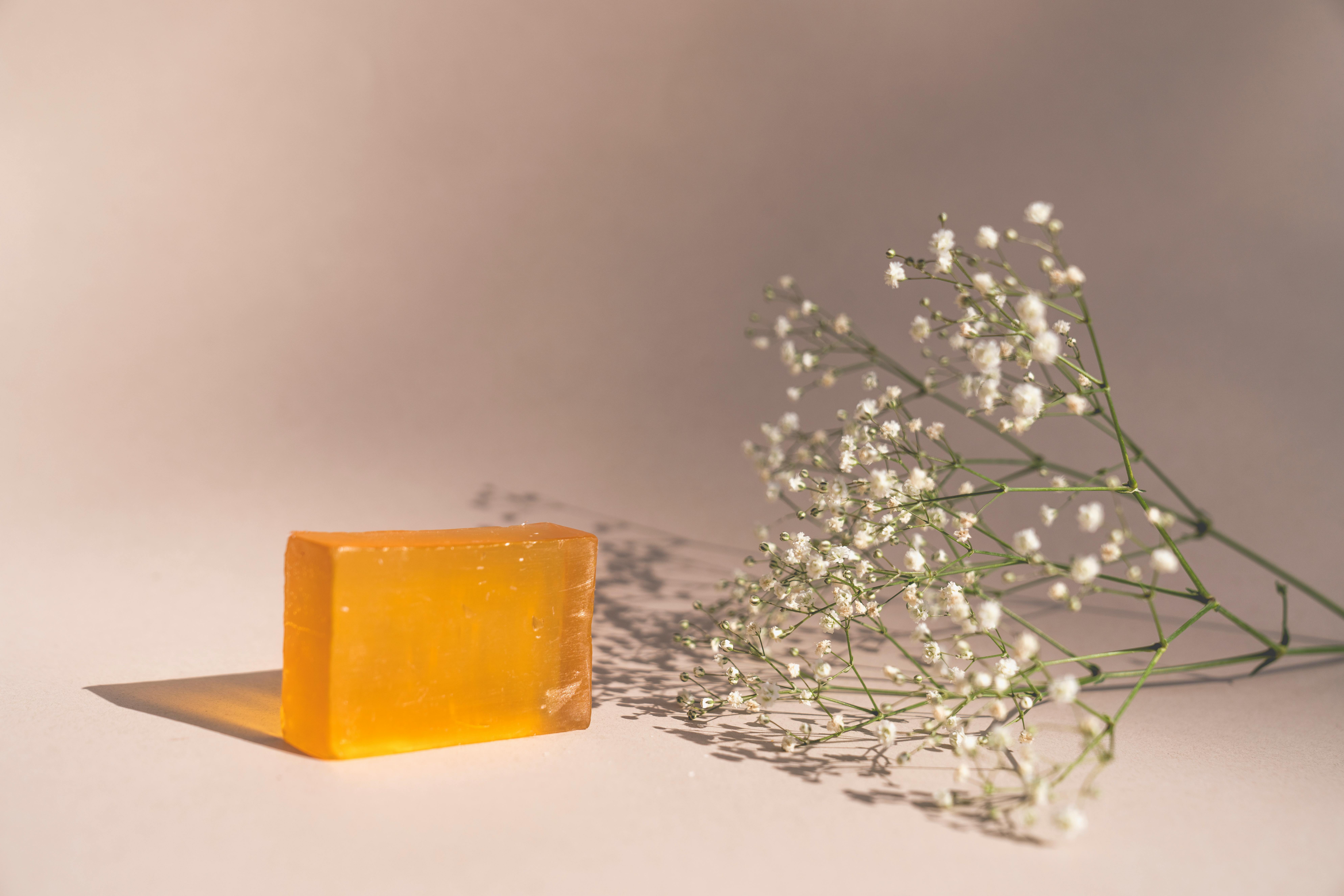 A bar of orange soap next to baby's breath flowers in a minimalist setup.