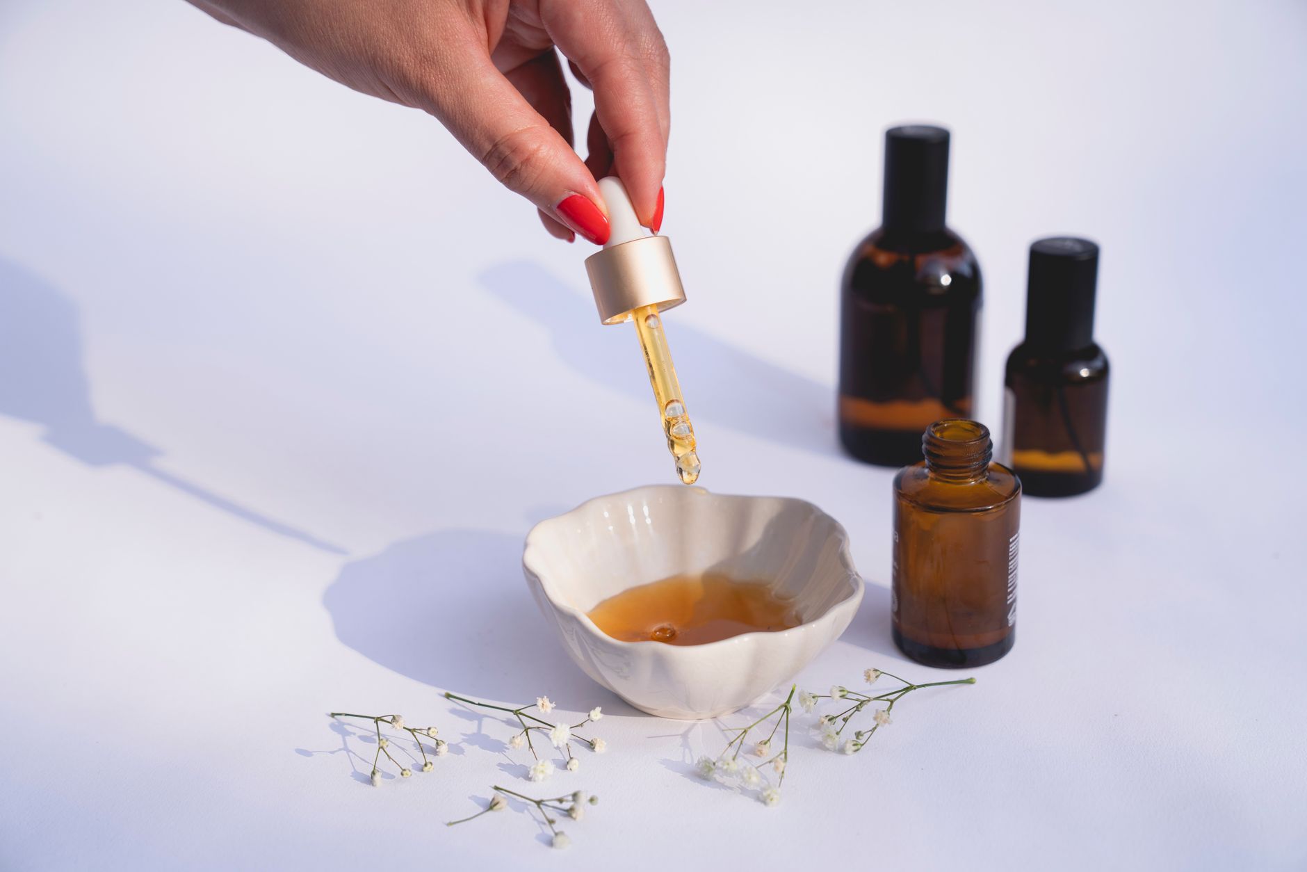 Stylish composition of a skincare routine with dropper bottles and dried flowers on a white backgrou