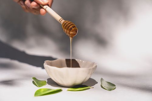 Honey flowing from a dipper into a ceramic bowl. Photo by Los Muertos Crew on Pexels