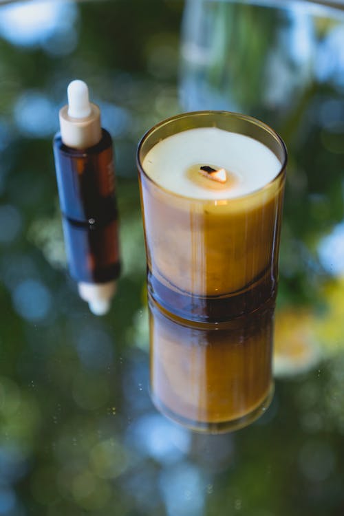 Natural oil in glass bottle placed near aroma candle