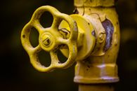 Close-up view of a rusty yellow shut-off valve, emphasizing industrial wear.