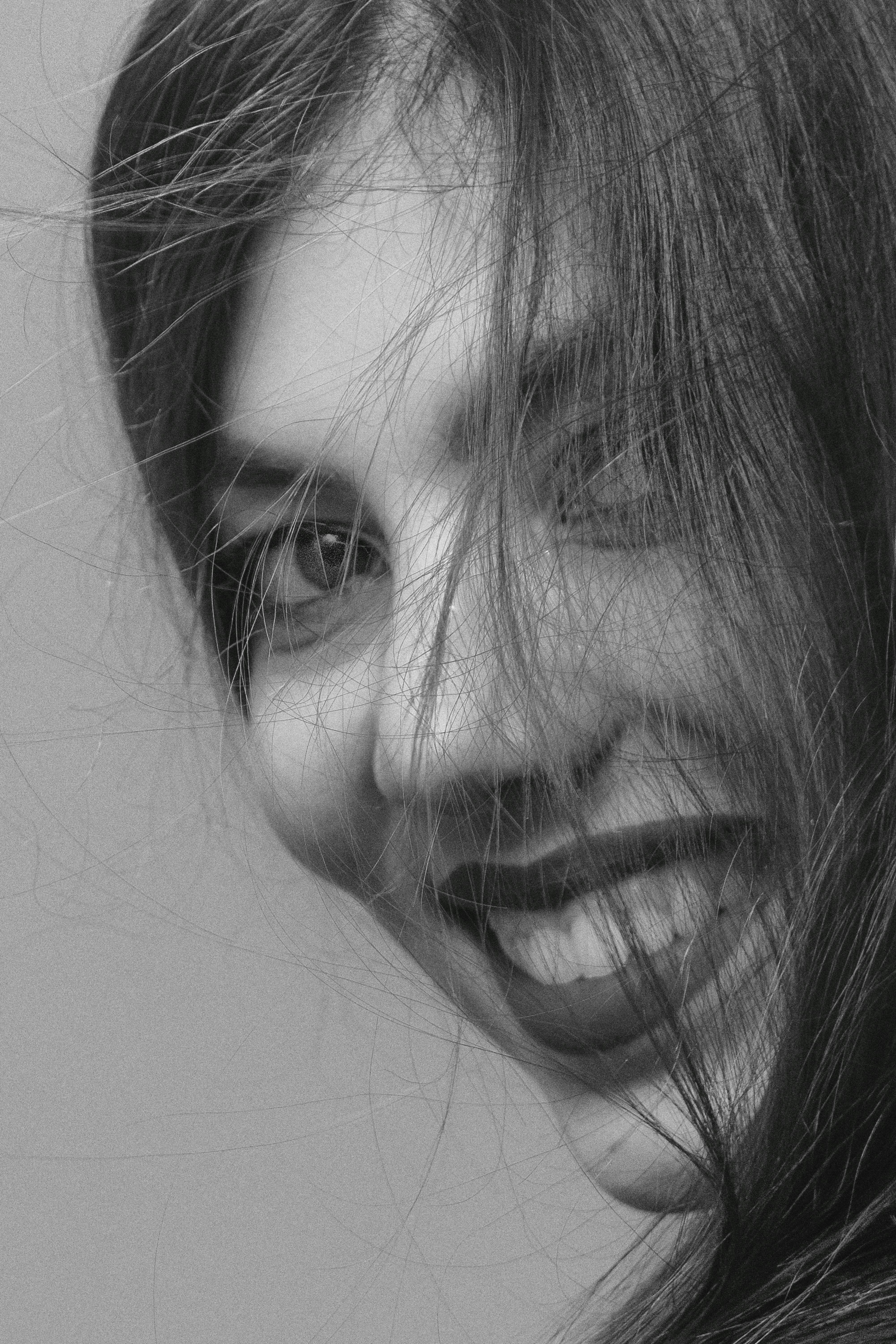 Artistic black and white portrait of a woman smiling, emphasizing her joyful expression.