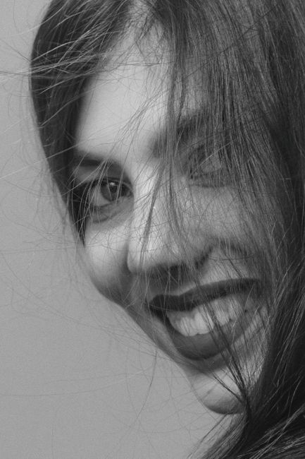 Artistic black and white portrait of a woman smiling, emphasizing her joyful expression.
