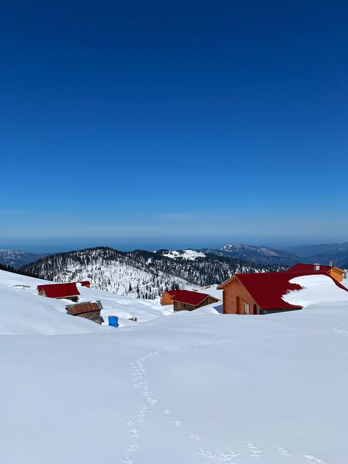 Free Scenic winter view of snow-covered houses and mountains in Rize, Türkiye. Stock Photo