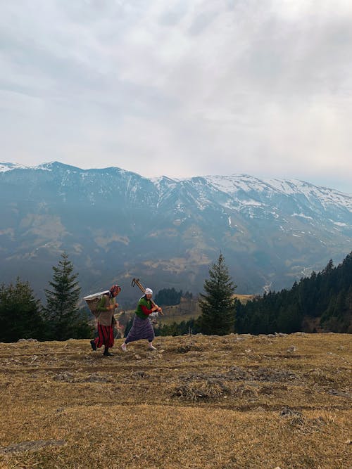 People Walking on Grass Near Snowy Mountains