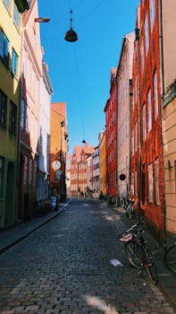 A vibrant cobblestone street lined with colorful buildings in Copenhagen, Denmark.