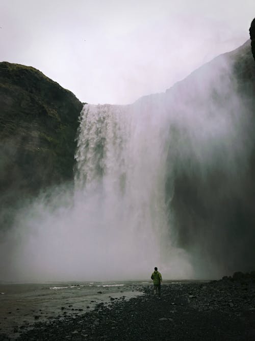 A Person Standing Near a Cascading Waterfall