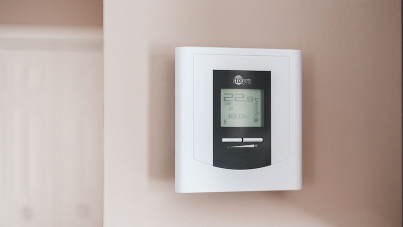 A close up of a digital smart thermostat displaying energy usage for a room cooling system