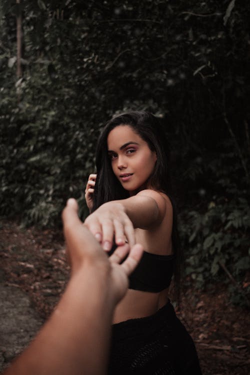 Person Holding the Hand of a Woman in Black Crop Top