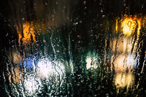Free Abstract view of city lights through raindrops on glass, creating a moody and colorful night scene. Stock Photo