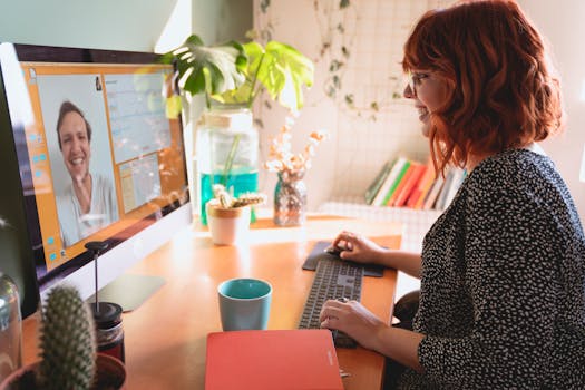 A woman video communicates from a sunny home office, enjoying a remote work setup.