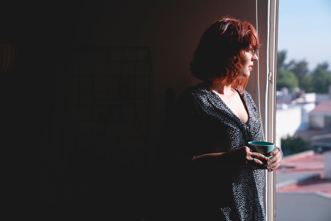 Free Woman Looking Outside while Holding a Mug Stock Photo