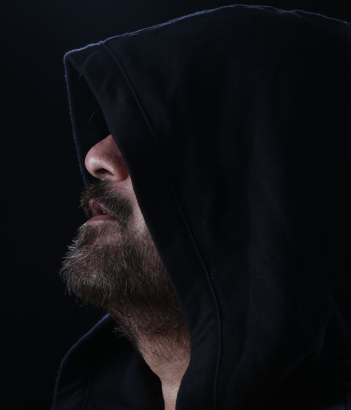 Moody hooded portrait in low studio light