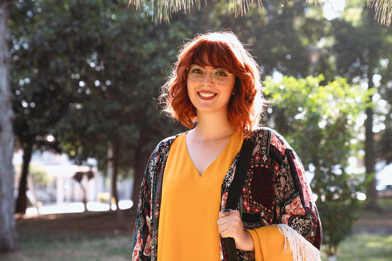 smiling redheaded woman with glasses enjoying a sunny day outdoors wea