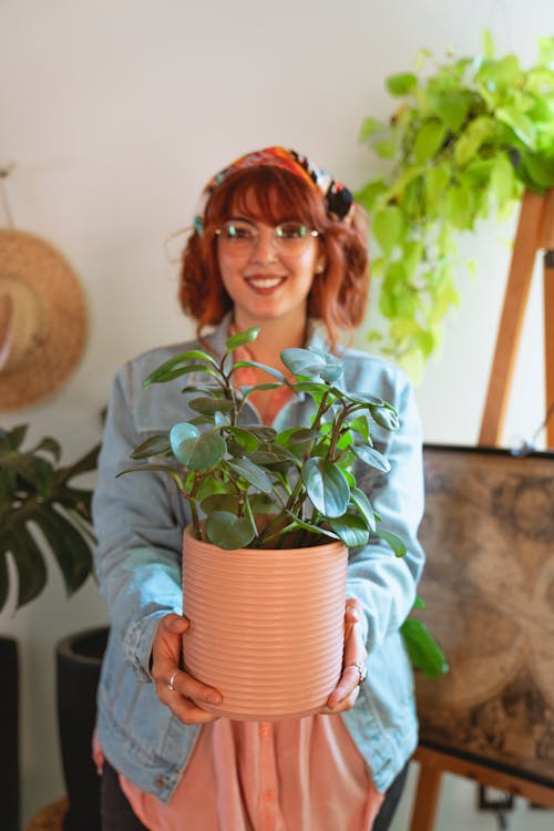 Woman in Light Blue Denim Jacket Holding a Plant