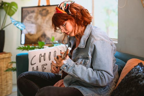 Woman in Light Blue Denim Jacket Playing Her Ukulele