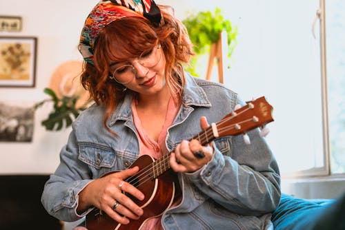 Woman in Blue Denim Jacket Playing Brown Acoustic Guitar