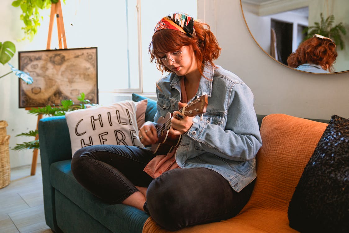 Woman in Light Blue Denim Jacket Playing Her Ukulele