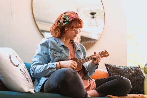 Woman in Light Blue Denim Jacket Playing Her Ukulele