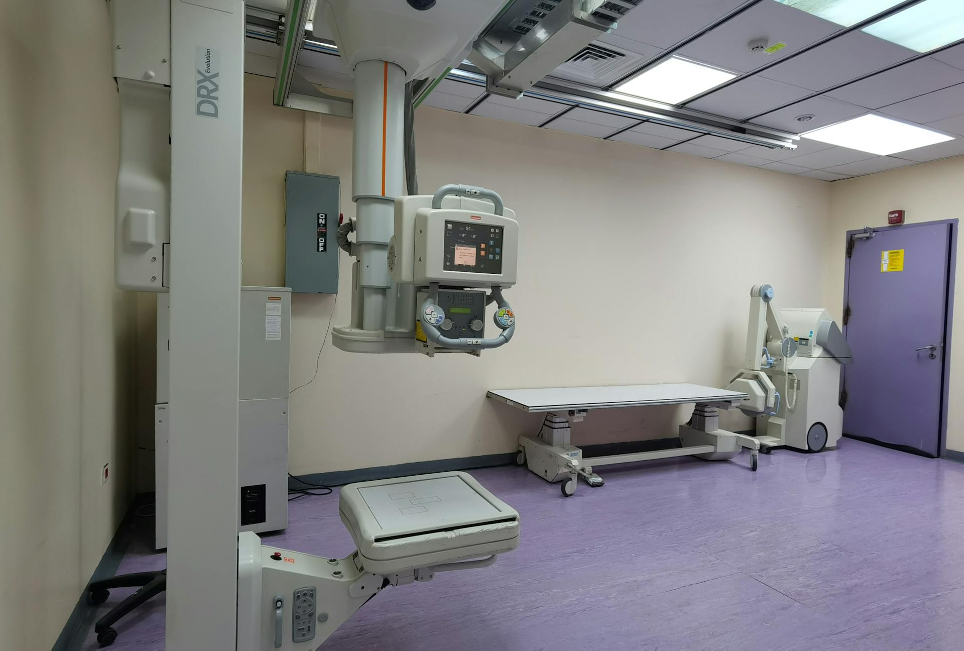 Interior view of a well-equipped hospital X-ray room with medical imaging devices.