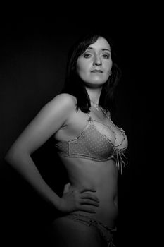 Striking black and white portrait of a woman posing elegantly in lingerie, showcasing timeless beauty.