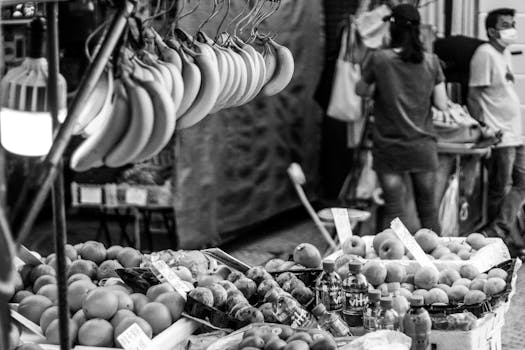 Monochrome image of a fruit market with bananas and apples on display.
