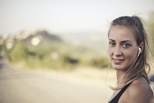 Smiling young woman with earphones jogging outdoors in Firenze, Italy. Sunny day with countryside view.
