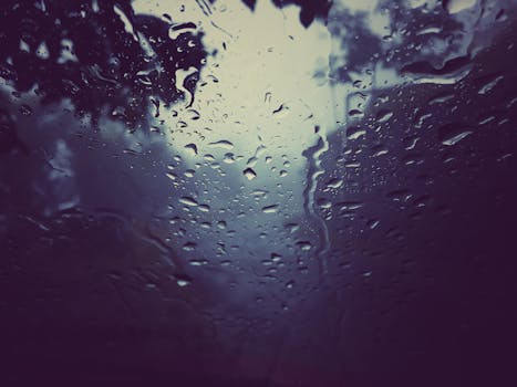 窗户上的雨滴特写喜怒无常，突出了雨天的纹理和气氛