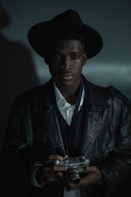 Free A Man Wearing a Leather Jacket Holding an Analog Camera Stock Photo