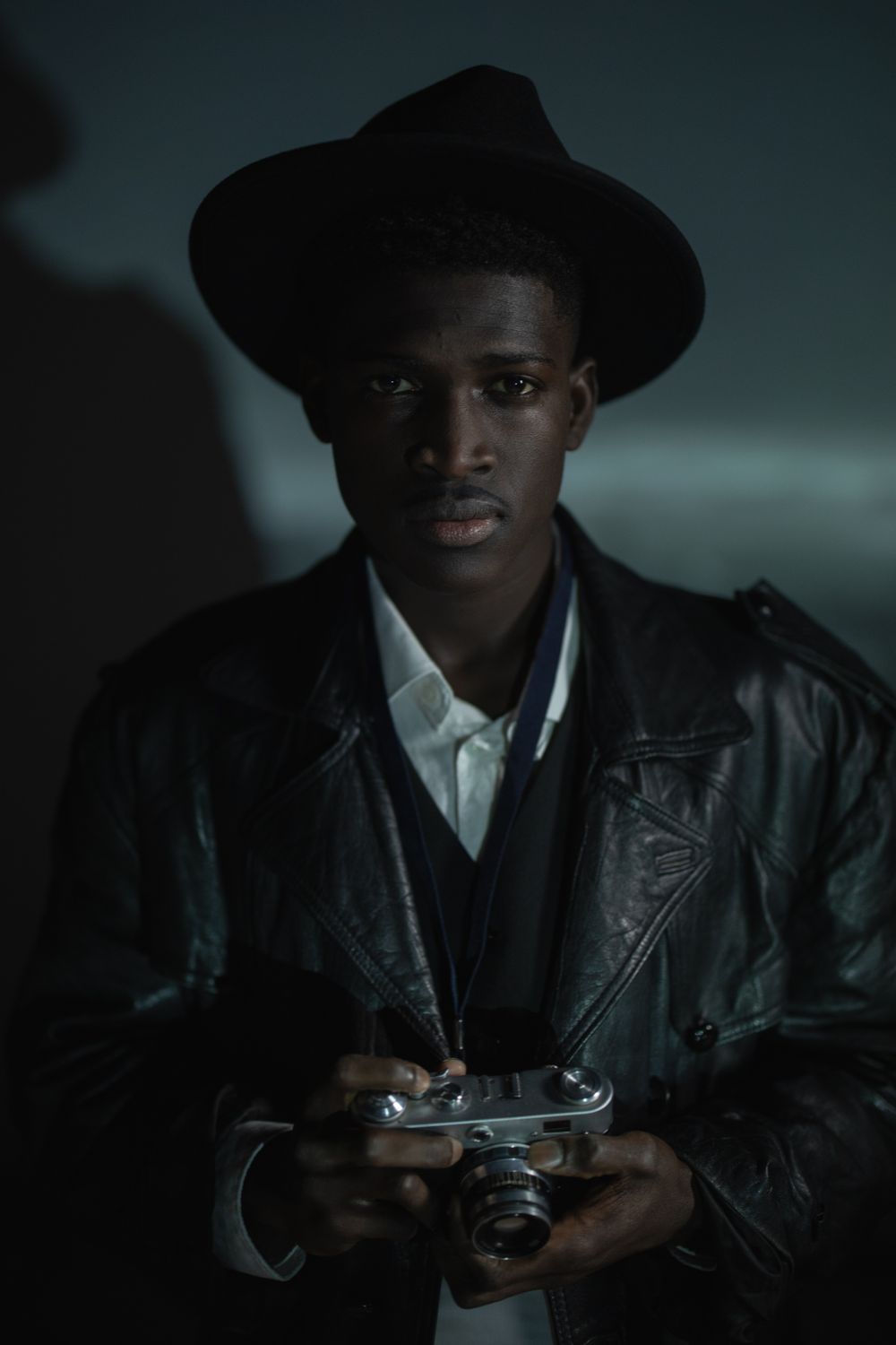 Photographer in a leather jacket holding an analog camera, portrait style