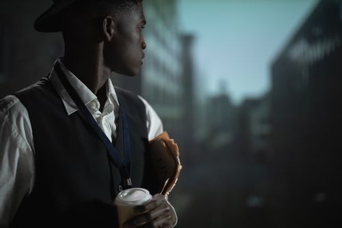 Free A contemplative man in an urban setting dressed as a detective, holding documents and coffee. Stock Photo