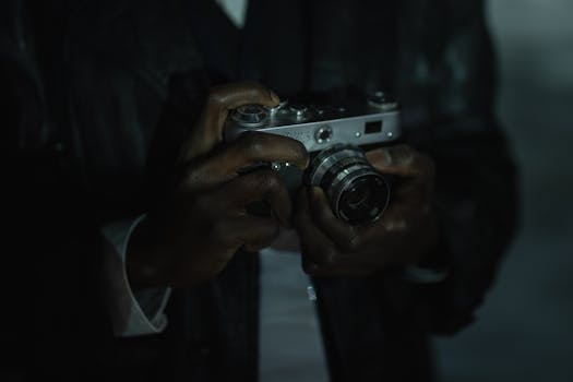 Moody close-up of a person holding a vintage film camera in dim lighting, highlighting craftsmanship.
