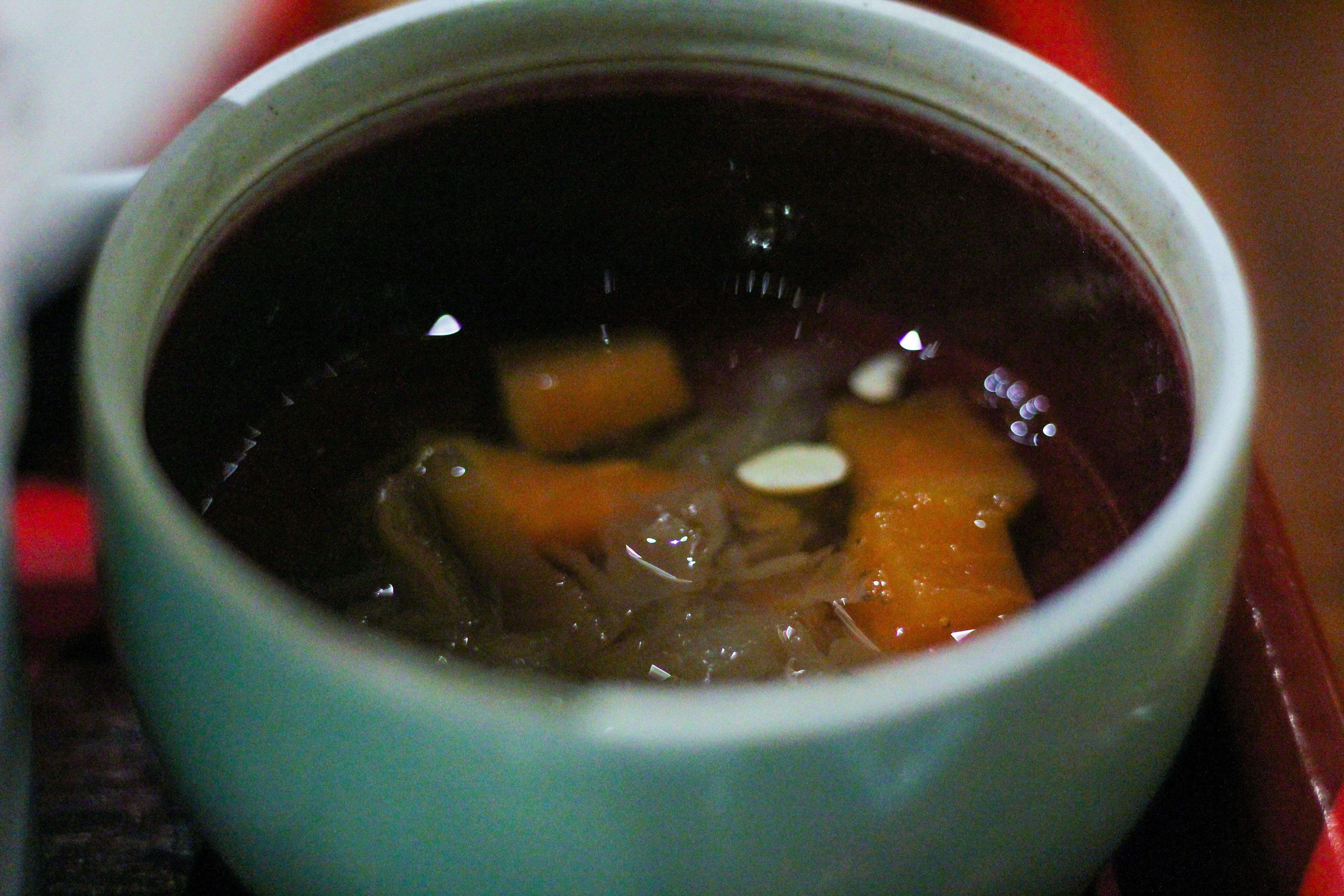Deux paires de mains, l'une plus âgée et l'autre plus jeune, préparant ensemble des légumes frais dans une cuisine.