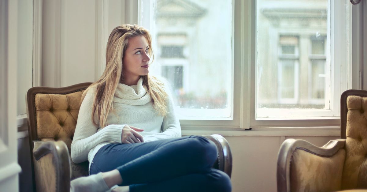 A serene moment of a woman in a cozy room, enjoying leisure time by the window.