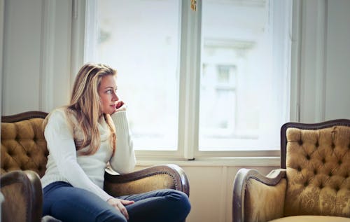 Fotografie Der Frau, Die Auf Stuhl Nahe Fenster Sitzt