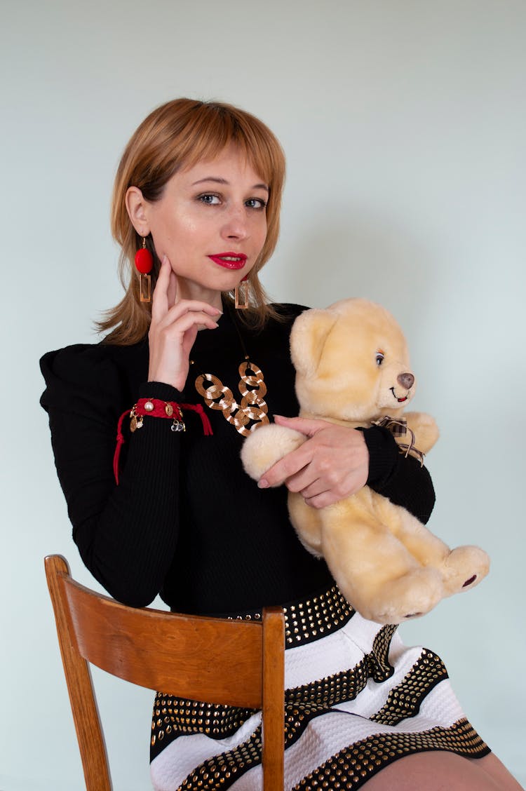 Stylish Woman With Toy Bear Sitting On Chair