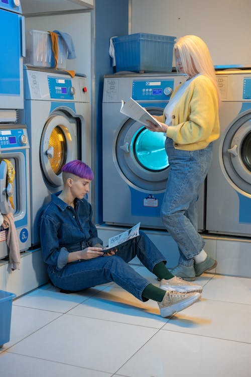 Women Reading Magazines Near Washing Machines