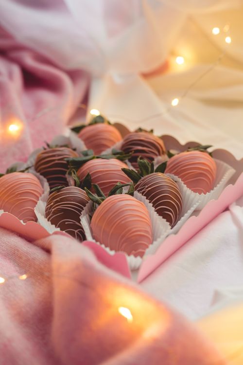 Free Tempting chocolate dipped strawberries in a box, surrounded by fairy lights. Stock Photo