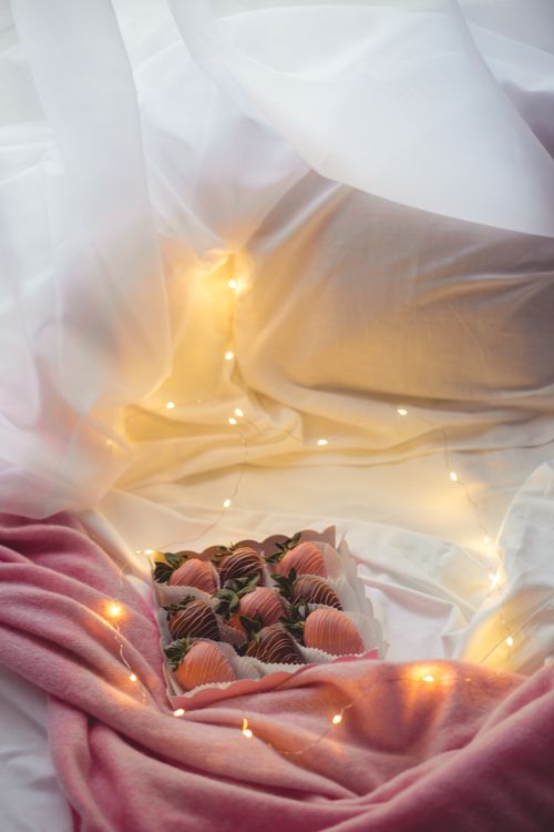 Free A box of chocolate-covered strawberries elegantly styled with pink fabric and fairy lights. Stock Photo